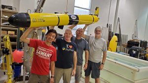 A group of researchers holding up a seaglider.