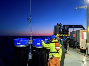 A group of crew members adjusting equipment aboard a research vessel.