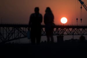 People watching sunset behind bridge