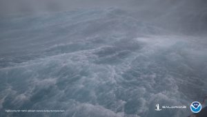 A large wave in the middle of the ocean in a storm.
