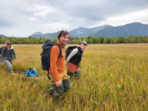 A group of researchers hiking through tall grass.
