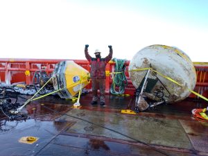 A researcher celebrating aboard the deck of a ship.