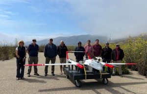 A group of researchers posing with an uncrewed aircraft.