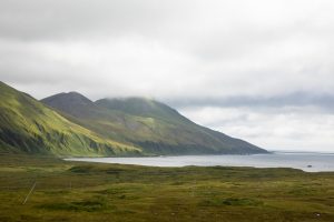 A small mountain in cloudy weather, with a bay at its base.