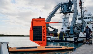 Orange saildrone being tied to a dock.