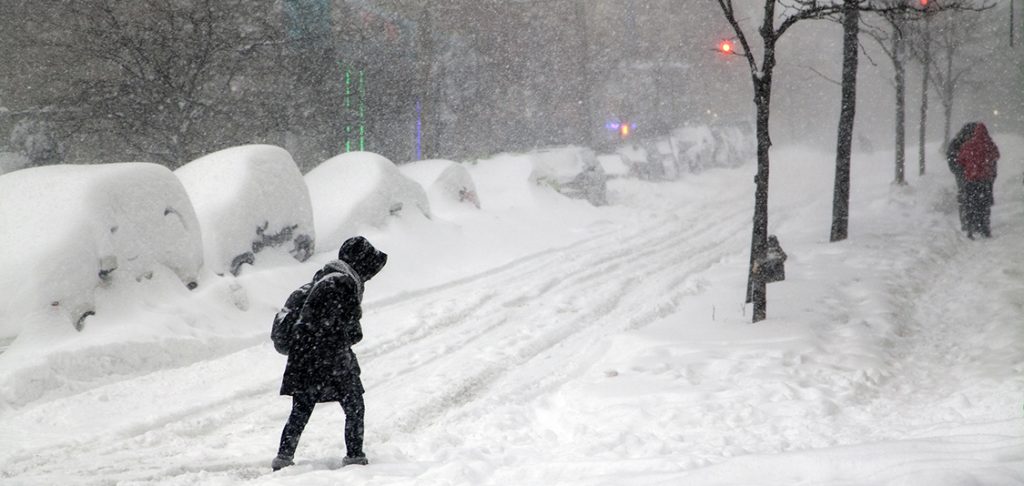 Woman crossing street during snow blizzard Jonas in the Bronx.