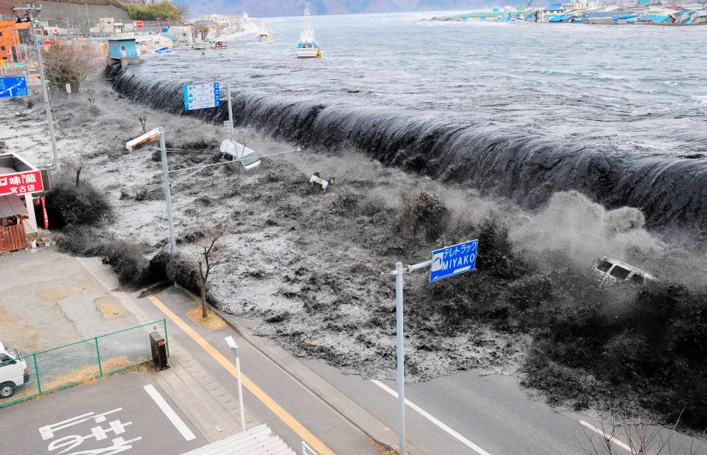 The 2011 Japanese tsunami caused immense devastation. Water overflows a sea wall and pours into a Japanese street.