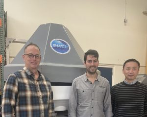 Three CICOES scientsists pose with a DART buoy. 