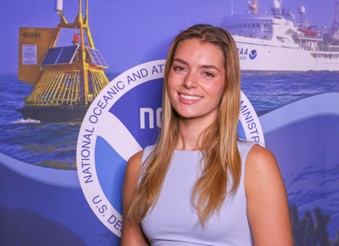 A headshot of Elize Herzfield standing in front of a NOAA graphical backdrop.