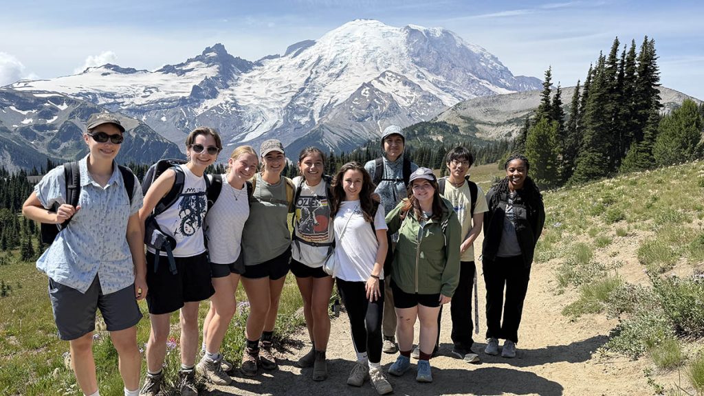 A group of CICOES interns hiking at Mt. Rainier National Park. Snowcapped Mt. Rainier is seen in the background. 