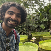 Headshot of Aakash Manapat. He poses near a floating lily garden. 