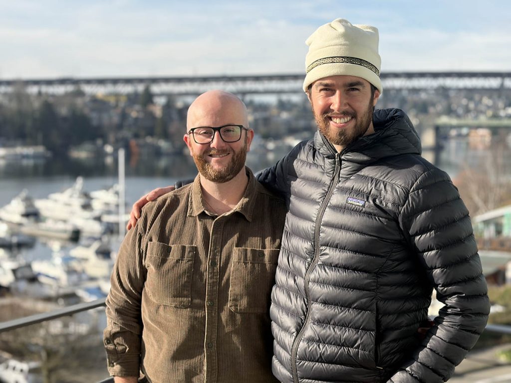 Two researchers pose on a deck with Lake Union in the background