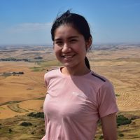 Headshot of Joyce Cai on a hike on a sunny day.