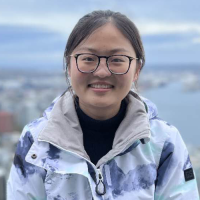 Headshot of Lin Yao, with a cityscape and large lake in the background.